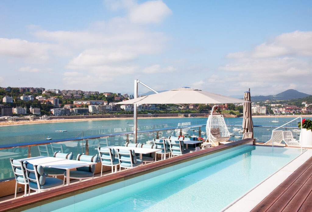 Vista de piscina completa con terraza con mesas y sombrillas